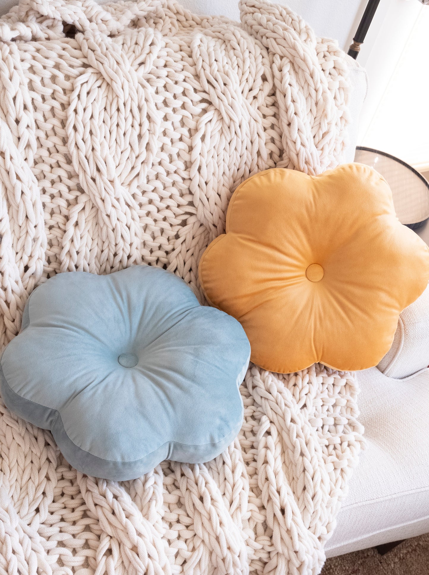 light blue and mustard yellow flower pillow on a sofa with a blanket