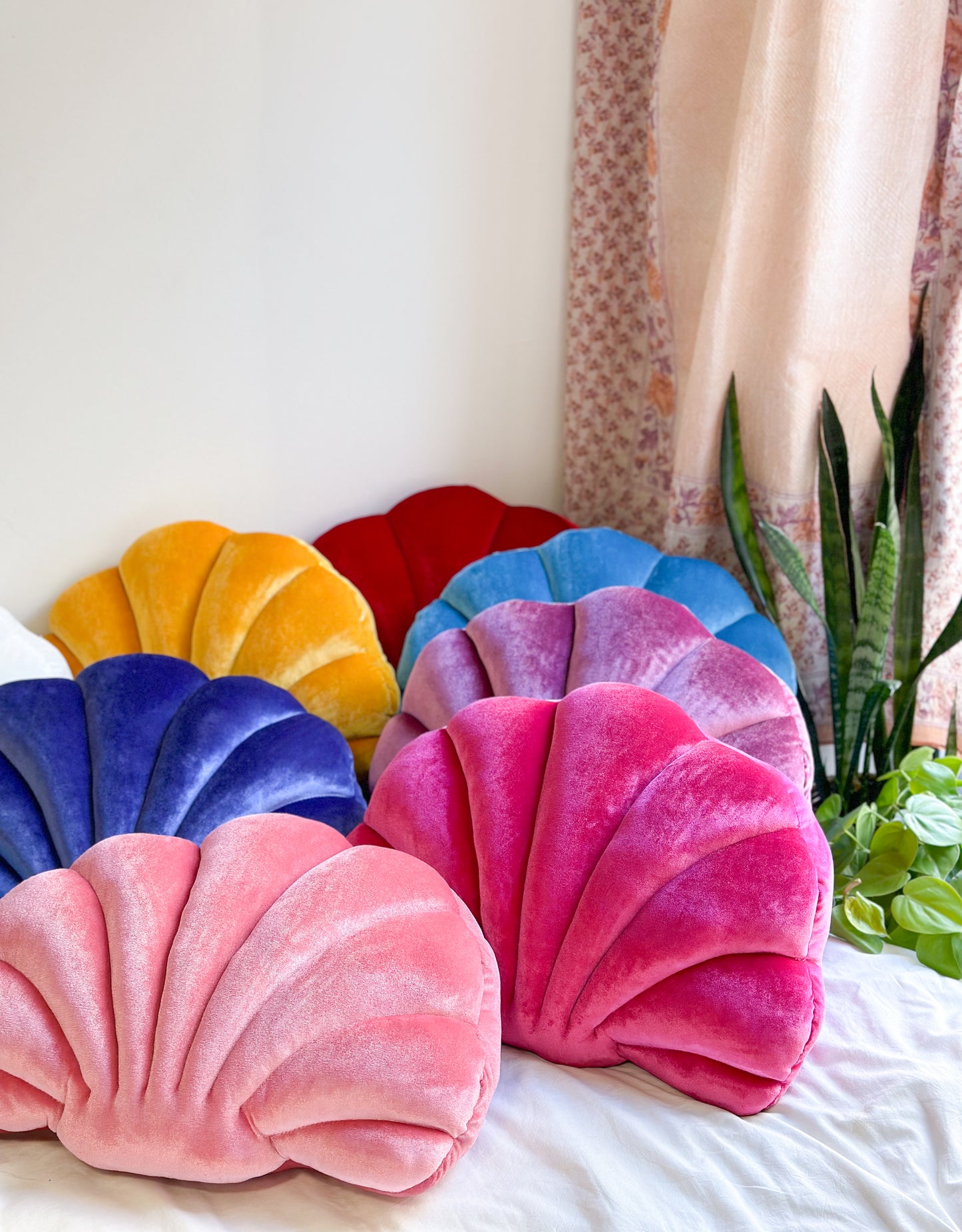 colorful shell shaped pillows on a bed