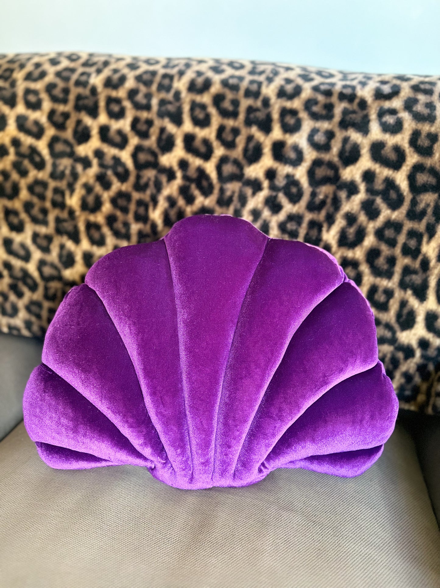 a purple shell pillow on a couch with a cheetah print blanket